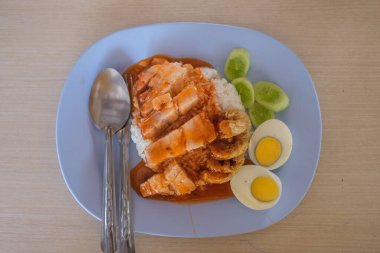 Kızarmış domuz eti soslu ve salatalıklı pilav üzerine yumurta.