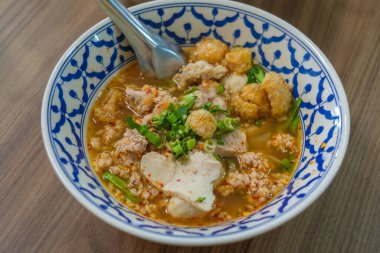 Sukothai usulü Tayland Tom-Yum çorbası. Arkaplan olarak ahşap tablo ile üst görünüm.