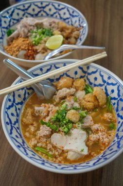 Sukothai usulü Tayland Tom-Yum çorbası. Arkaplan olarak ahşap tablo ile üst görünüm.