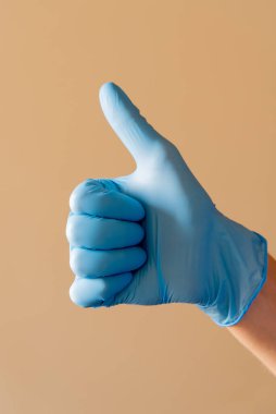Parlak mavi eldiven giyen bir insan, olumlu ve dostça bir jest olarak parmaklarıyla tanınmış bir barış işareti yapıyor.