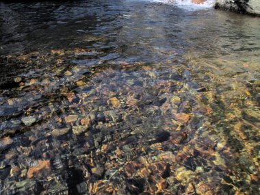 Temiz göl ve suyun altında çok renkli taşlar görülebilir.