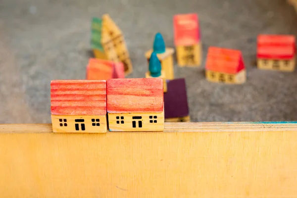 stock image Small wooden toy houses. Building homes on sand. Children game. Five cottages with red roof on grey soil. Modelling village. Construction and architectural concept. City in miniature. Creativity