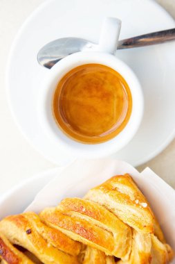 Geleneksel İtalyan kahvaltısı. Küçük beyaz bir fincan sıcak kahve ristreto ve elma ve fındıklı iki taze kruvasan. Günaydın konsepti. Gün ışığı. Ev yapımı fırın. Ginseng sıcak içeceği ve elmalı turta.