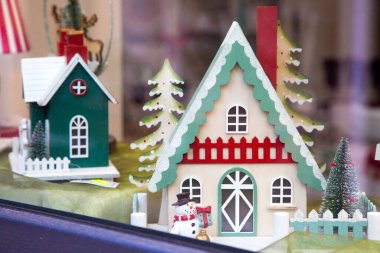 Hoş süslemelerle süslenmiş ve önünde neşeli bir kardan adamın durduğu büyüleyici yeşil ve beyaz zencefilli kurabiye evi.