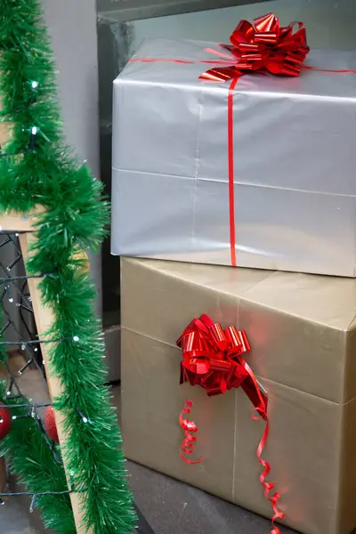 Üstünde parlak kırmızı bir fiyonk ile süslenmiş bir yığın renkli Noel hediyesi, festival sezonu için hazır.