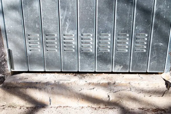 Sağlam metal dolaplardan oluşan düzenli bir sıra titizlikle katı, desenli tuğla bir zemine dizilmiş, organize bir görünüm yaratıyor.