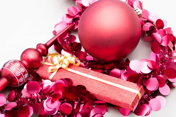 Canlı kırmızı bir Noel süsü, şenlikli atmosferi güzelleştiren bir dizi pembe dekorasyonun arasında güzel bir şekilde duruyor.