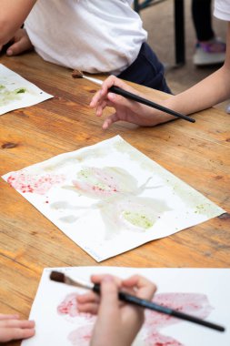 Genç bir çocuk neşeli bir şekilde renkli bir kelebek tasarımı çiziyor canlı renkler ve heyecan verici desenlerle, yaratıcılığını ifade eden bir kağıt parçasına.