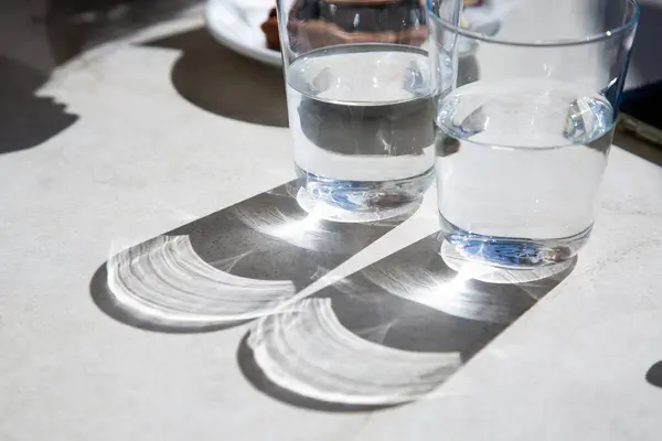 Bir masada, iki bardak ferahlatıcı su vardır sessizce oturur, sık sık kullandığımız basit ama temel içki takımlarını sergilerler.