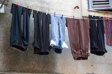 Çeşitli giysiler zarif bir şekilde binanın dışındaki bir ipte asılı duruyor, rüzgarda hafifçe salınıyor.