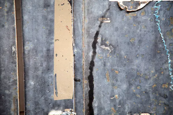 Bu, çeşitli buruşuk kağıt parçalarının etrafa saçıldığı desenli metal bir yüzeyin yakından görüntüsü, ilginç bir görsel yaratıyor.