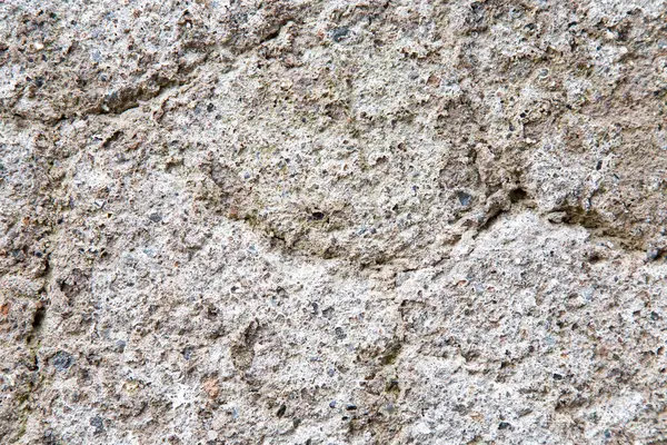 Bu, yüzeyine ve dokusuna yerleştirilmiş önemli sayıda küçük taşı barındıran beton bir duvarın yakın plan görüntüsü.