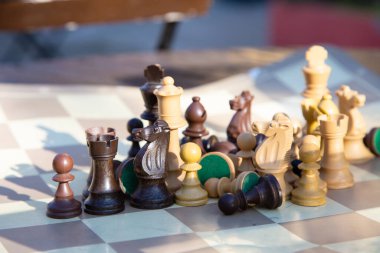 Karmaşık bir şekilde tasarlanmış ahşap satranç taşları koleksiyonu stratejik olarak oyun oynamaya hazır klasik bir satranç tahtasına yerleştirilir.