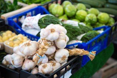 Rengarenk sebzelerle dolu ahşap bir sandığın üzerinde satılmaya hazır bir sürü taze sarımsak duruyor.