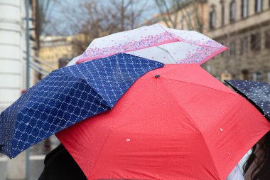 Renkli bir şemsiye koleksiyonu birbiri ardına zarif bir şekilde üst üste istiflenir, canlı renkler ve desenlerin karışımını sergiler.