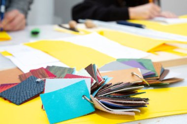 Çeşitli kumaş örneklerinin bir koleksiyonu sağlam bir tabloda gösterilir, potansiyel seçilim için farklı doku ve renkler sergilenir