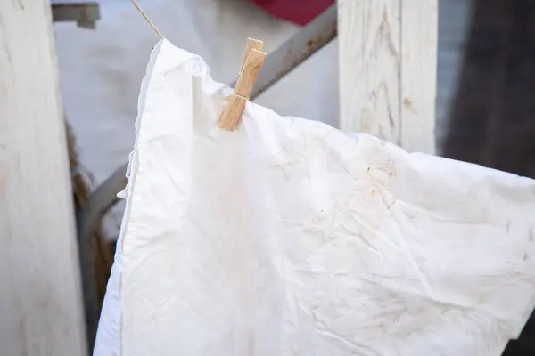 Beyaz bir bez parçası zarif bir şekilde bir ipte asılı, hafif bir esintiyle sallanıyor, parlak ve temiz görünümünü sergiliyor.