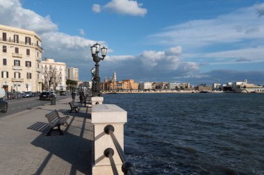 Bari, İtalya (8 Nisan 2025) - İtalya 'nın Bari kentinde, asfalt yol boyunca klasik sokak lambaları ve bankların yer aldığı sahil yürüyüşü. Adriyatik Denizi sağda, yumuşak bir dalgayla