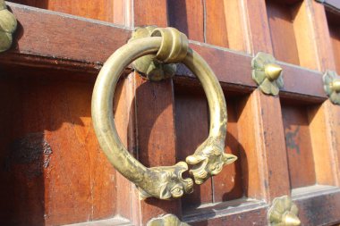 Detail of a bronze knocker on a wooden door clipart