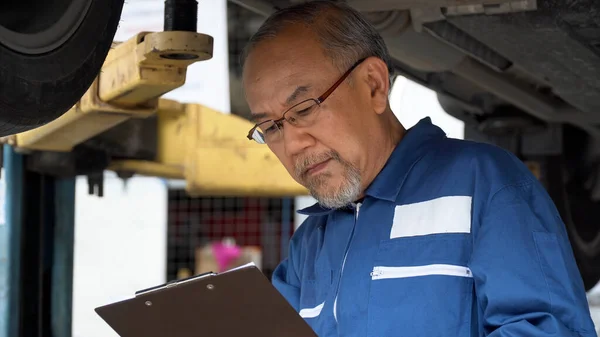Asiatische Mechaniker Senior Mann Mit Clip Board Checkliste Bremse Reifen Stockbild