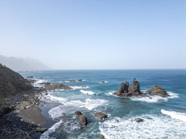 Kayalık bir uçurumu ve bir su kütlesi olan bir sahil.