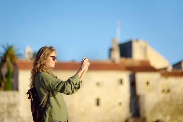 在布德瓦老城区 年轻的女游客用智能手机拍照非常迷人 迷人的红头发姑娘在日落时欣赏古城 黑山的旅游和观光 单人旅行 — 图库照片