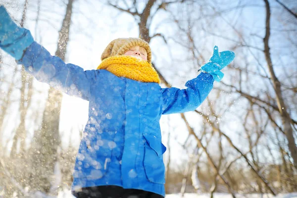 手から新鮮な雪を投げつける少年 子供たちは雪の日に公園を歩くのを楽しむ 雪の中で楽しい赤ちゃん 子供連れの家族のための屋外冬の活動 — ストック写真