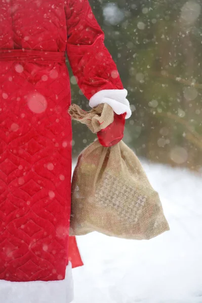 クリスマスの贈り物の袋を持つサンタクロースは雪の森を歩いています サンタクロースの衣装のアニメーターや親は子供のための休日に急いでいます 冬休みに関する伝統 — ストック写真