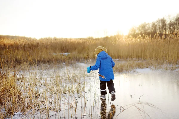 可爱的学龄前男孩在寒冷 阳光灿烂的冬日落日下 在冰封的湖面或河流上玩耍 孩子们在家庭远足时滑行和玩乐 儿童冬季户外运动 — 图库照片