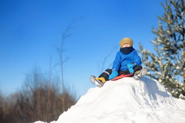 小さな男の子は雪の日に氷のスライドに乗るのを楽しむ 吹雪の中で楽しい赤ちゃん 子供連れの家族のための屋外冬の活動 — ストック写真