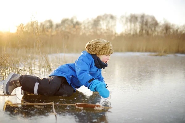 寒い日当たりの良い冬の夕日に凍るような湖や川の氷の上にかわいい未就学児が落ちました 冬の子供の屋外ゲームの危険性 — ストック写真