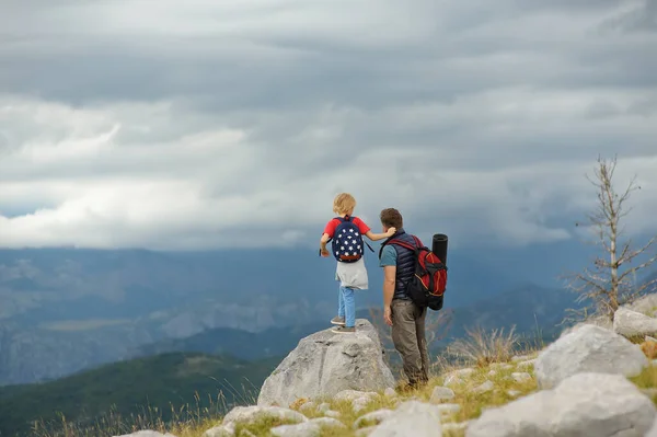 かわいい子供と彼の成熟した父親は山で一緒にハイキングし 自然を探索します 子供は雲を見ている 子供連れの家族のための冒険 スカウティング バックパッキング観光の概念 — ストック写真