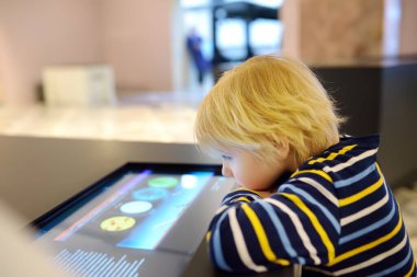 Küçük beyaz çocuk bir bilim müzesinde sergi arıyor. Keen çocuk sergileri keşfediyor. Çocuklar için eğitim ve eğlence. Anaokulu çocukları olan aile aktiviteleri.