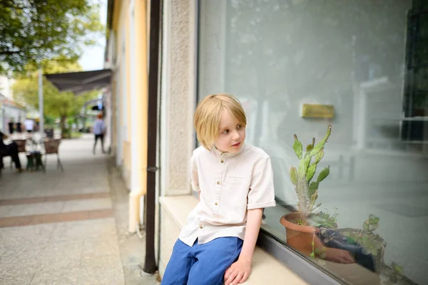 A small child walks around a small town in Europe. A boy of school age looks at the shop windows. The concept of a family weekend in the city.