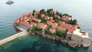 Tarihsel kenti olan Sveti Stefan adasının inanılmaz günbatımı hava aracı görüntüsü. Montenegro 'da yer alan Adriyatik Denizi' nin en aşağı manzarası. Balkan 'da ünlü turistik ilgi odağı..