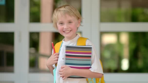 幸せな学校の子供のスローモーションの肖像画 可愛い子は感情的に笑い あなたを見ています 学校のドアで学年の開始前に楽しい少年 学校に戻る — ストック動画