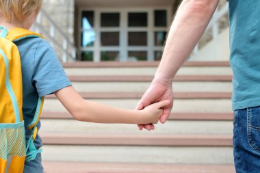 Little schoolboy with his father goes to school after summer holiday. Parent accompanies or meets the child. Quality education for children. Kids back to school concept.