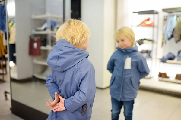 Милый Мальчик Примеряет Новое Пальто Перед Зеркалом Магазине Торговом Центре — стоковое фото