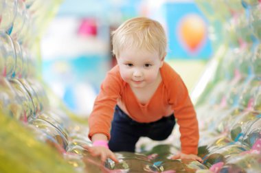 Aktif çocuk eğlence merkezinde şişirilebilir bir cazibe yaşıyor. Komik çocuk kapalı alanda oyun oynuyor. Çocuklar için eğlence parkı.