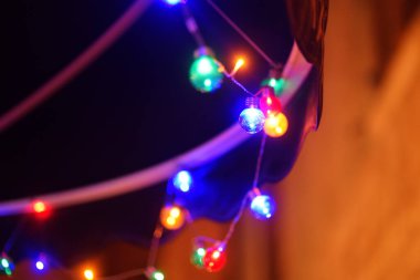 Akşam vakti bahçedeki ağaçta asılı duran ipli ışıkların fotoğrafı. Gece partisi için ampullü moda dekorasyonu. Açık hava elektrik lambaları