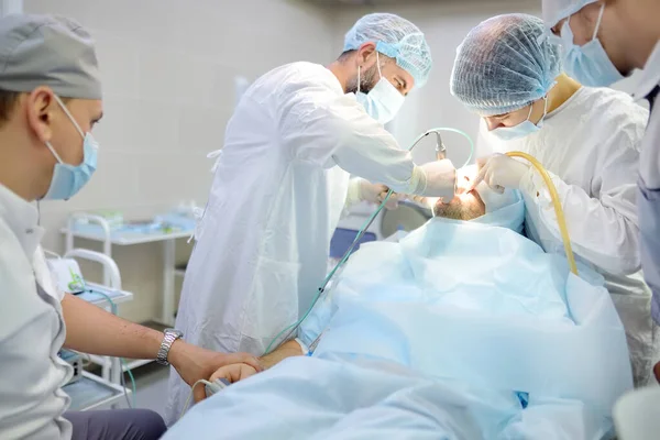 Surgeon and nurse during a dental operation.Anesthetized patient in the operating room. Installation of dental implants or tooth extraction in the clinic. General anesthesia during orthodontic surgery