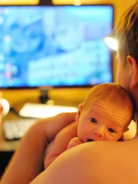 成熟的父亲抱着他可爱的新生婴儿在家里的电脑上工作 在家办公和为人父母的同时 为人父母自由职业者 — 图库照片