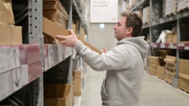 Belgrad, Sırbistan - 5 Mart 2023: Orta yaşlı bir adam IKEA mağazasından veya depodan bir kutu aldı. IKEA dünyanın en büyük mobilya perakendecisi ve mobilya montajı için hazır satıyor..