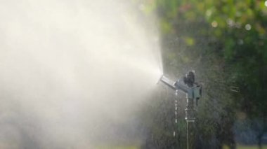 Halka açık bir parkta bahçe fıskiyesi. Bahçe malzemeleri. Güneşli bir yaz gününde bahçedeki çimleri sulamak.