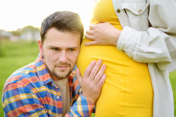 若い家族は赤ん坊を期待している 妊娠中の女の腹を触り子供の動きを感じるハンサムな男 両親の幸せなカップルになるために — ストック写真