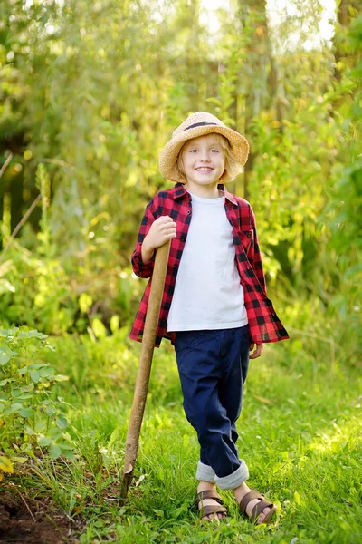 夏天阳光明媚的时候 小男孩拿着铲子在自家花园里干活 与小学生一起进行家庭园艺活动 村里孩子们的暑假 — 图库照片