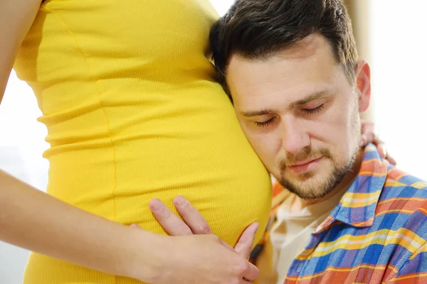 年轻的家庭要生孩子了 英俊的男人摸着孕妇的腹部 感受孩子的动作 一对幸福的准父母 — 图库照片