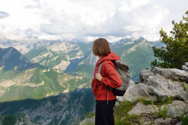 Yürüyüş sırasında dağ vadisinin kayalık yamacında duran kadın yürüyüşçünün yan görüntüsü. Genç bir kadın Avrupa Alpleri 'nde yürüyüş yaparken kayalık tepeli manzaranın keyfini çıkarıyor..