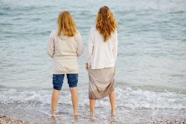 红头发的老年母亲和她的成年女儿一起沿着海滨散步 见到一个母亲和她的大孩子很高兴 成年子女与年长父母之间的家庭关系 — 图库照片