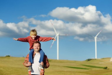 Eco activists man and child on background of power stations for renewable electric energy production. People and windmills. Wind turbines for generation electricity. Green energy concept